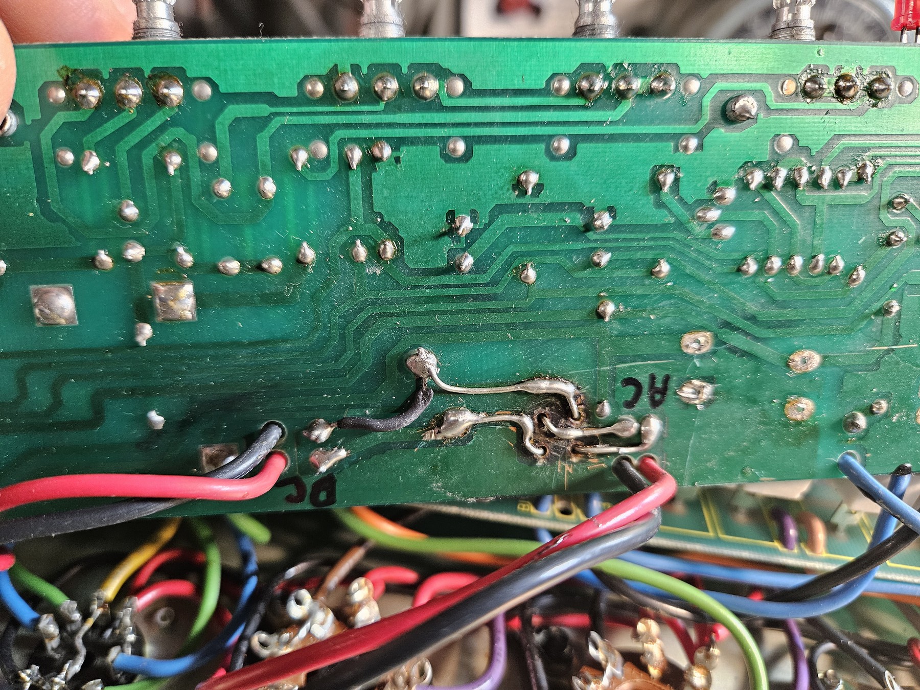 Damaged circuit board with jumper wires bypassing burnt traces